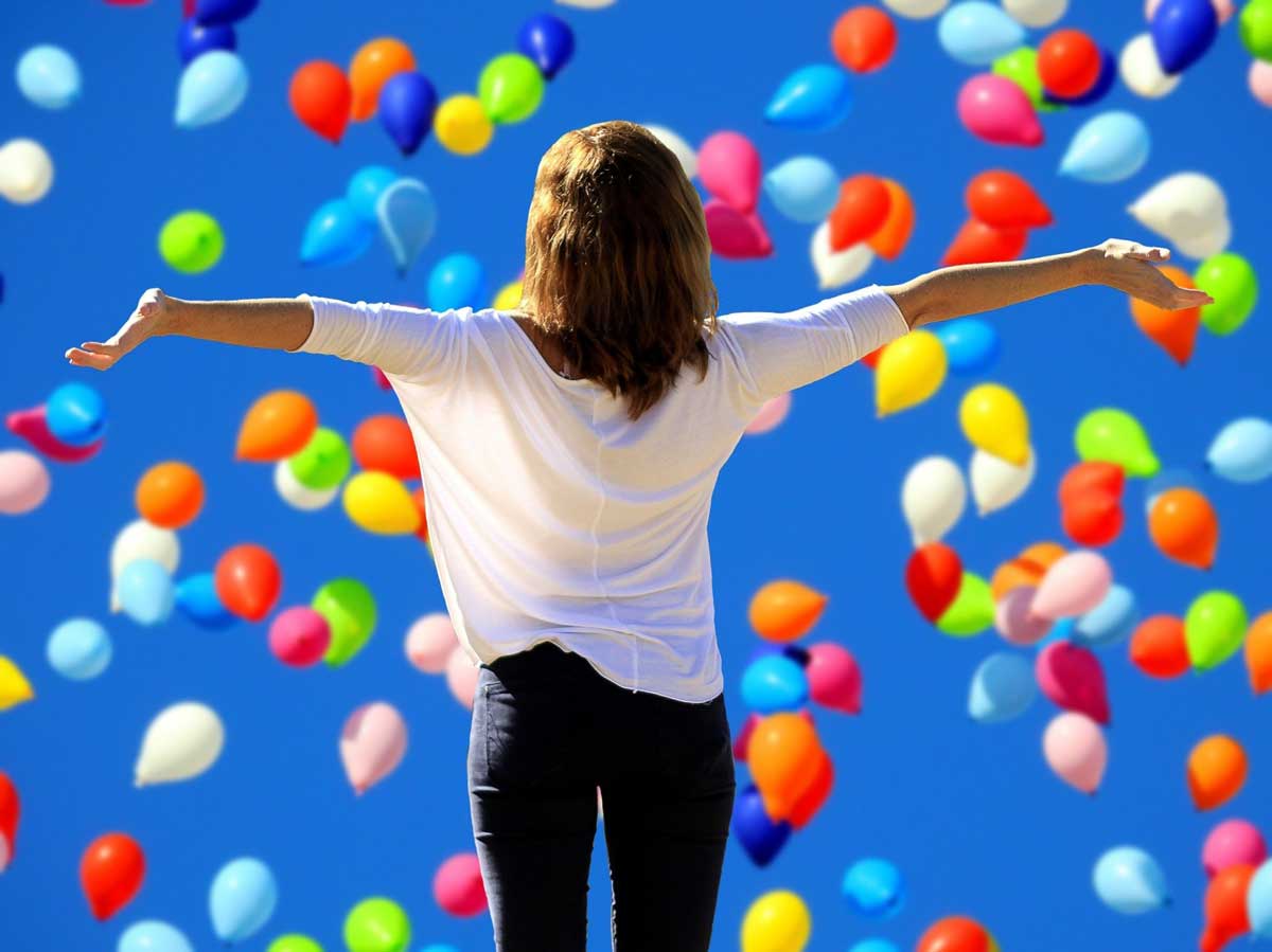 photo of joyful woman with balloons in sky.