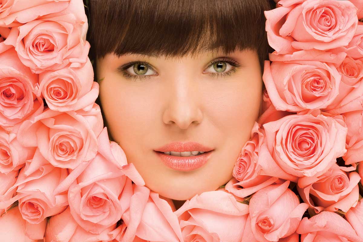woman's face surrounded by salmon color roses.