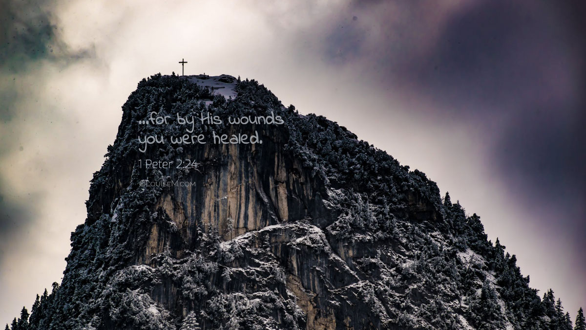 cross on rocky hill in black and white says by his wounds you have been healed.
