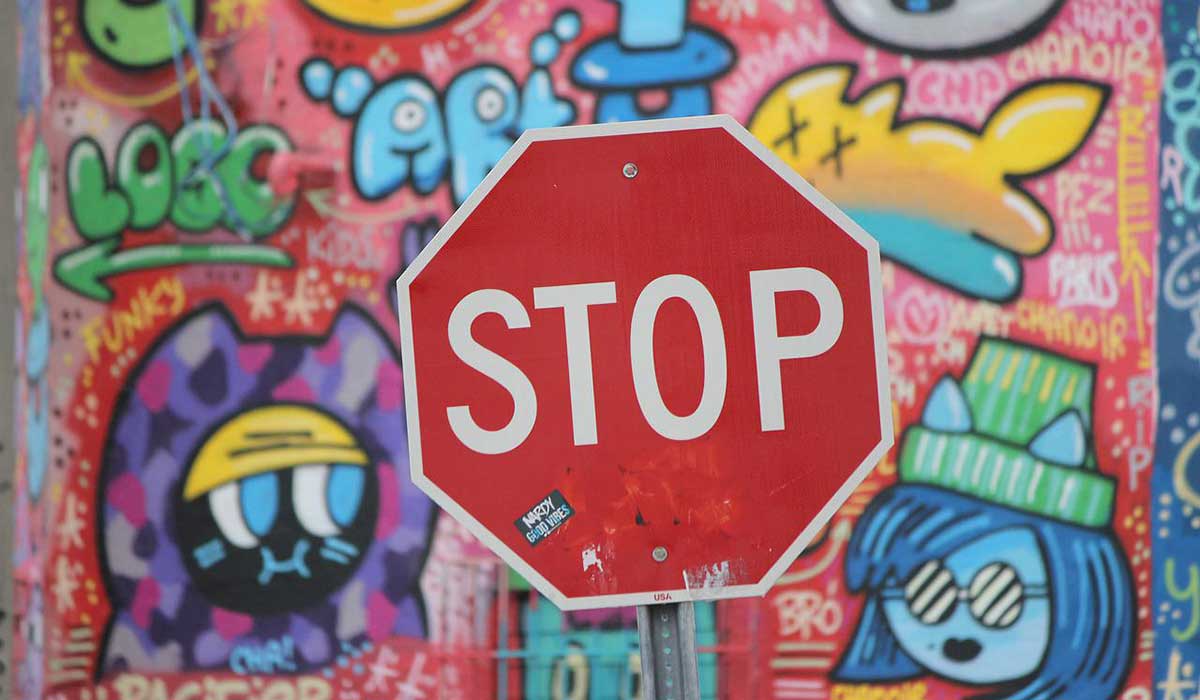 red stop sign on colorful graffiti still grabs attention.