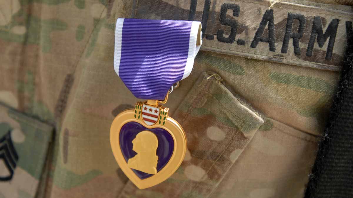 closeup of army uniform with Purple Heart pinned on pocket.