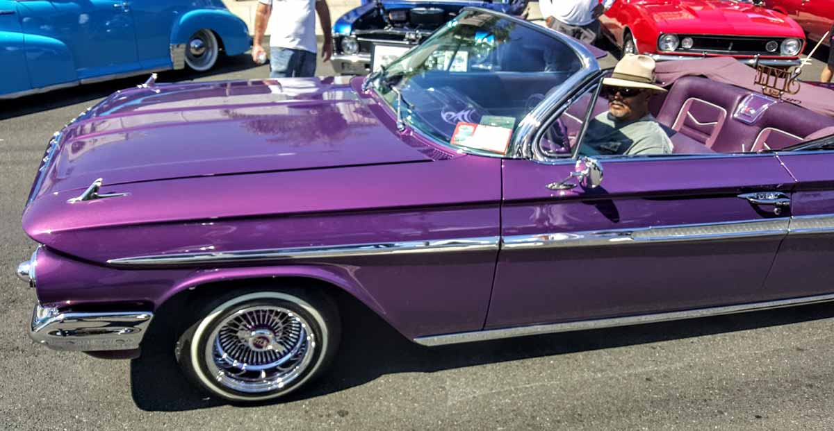 Flashy purple vintage Impala car at car show.