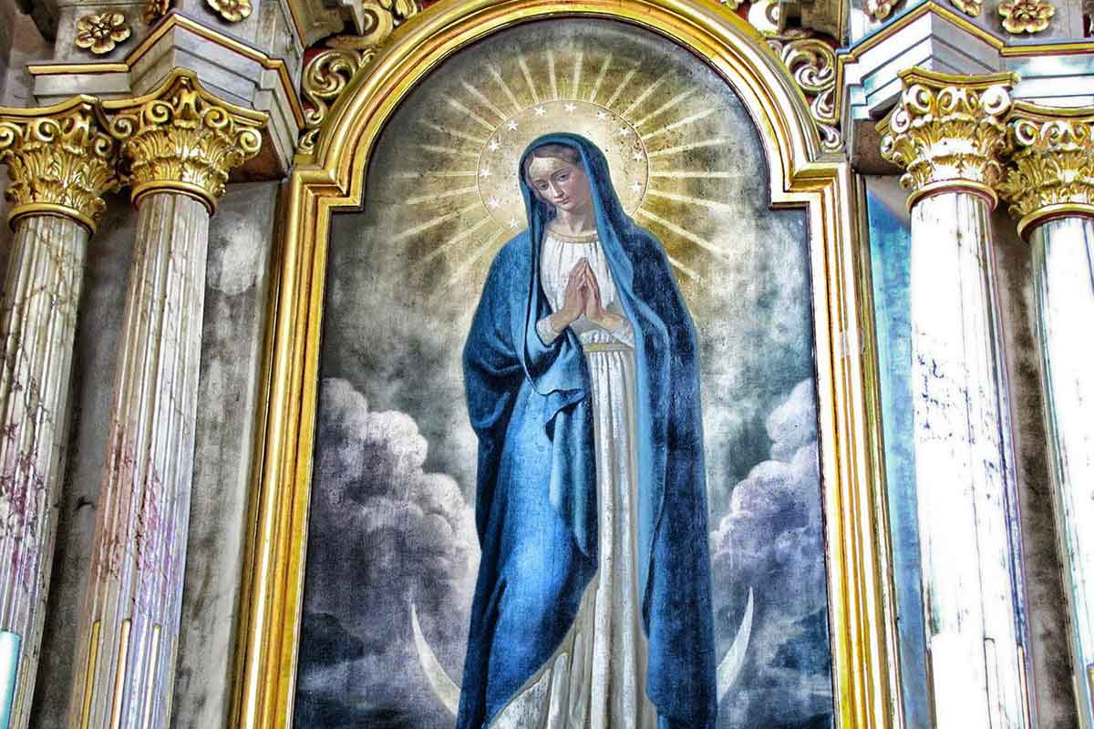 painting of virgin mary wearing rich blue robes and surrounded by gold leaf arch and columns.