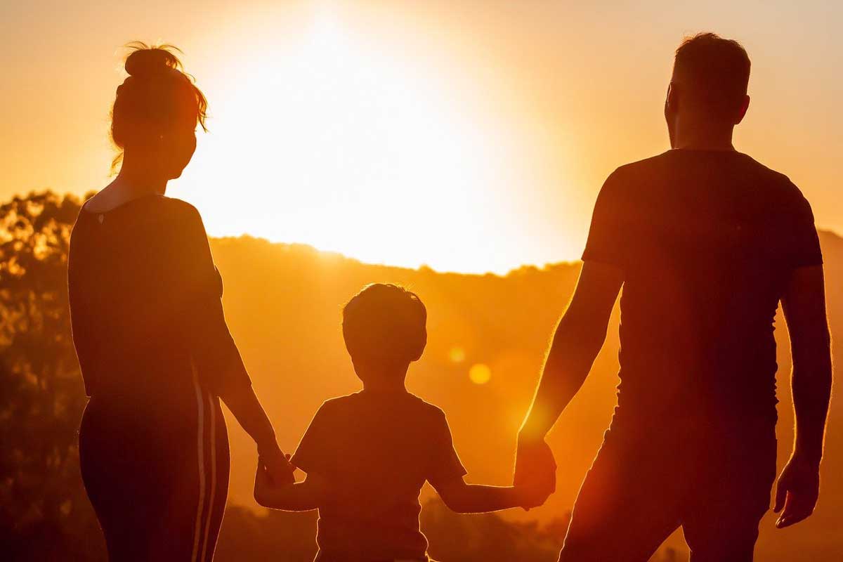 silhouette of family in front of sun setting.