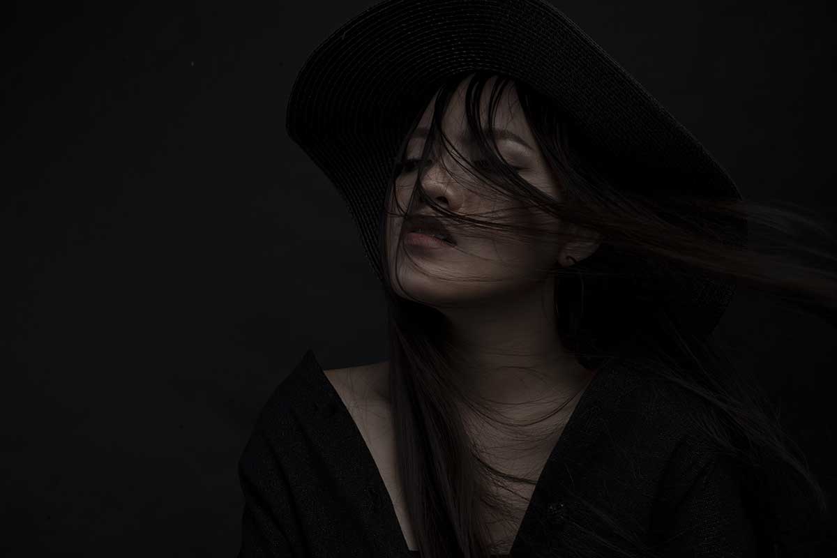 mysterious woman shrouded in black looks pensive.
