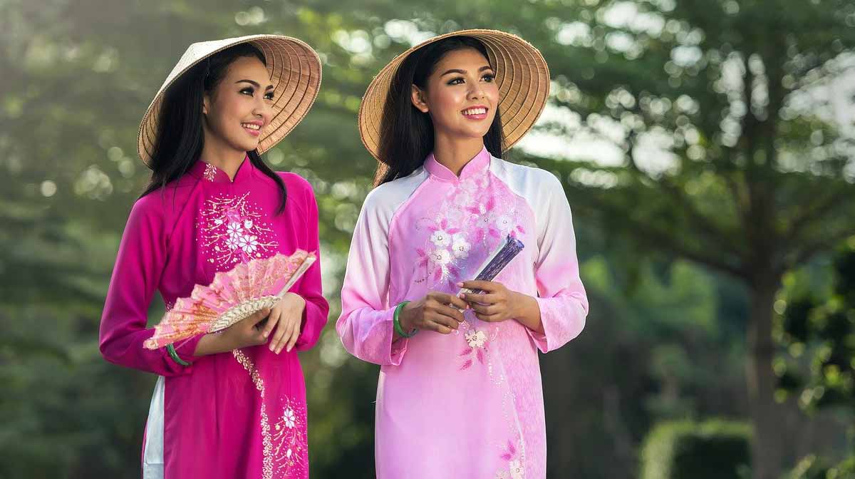 two asian ladies wearing traditional chinese dresses in shades of pink.